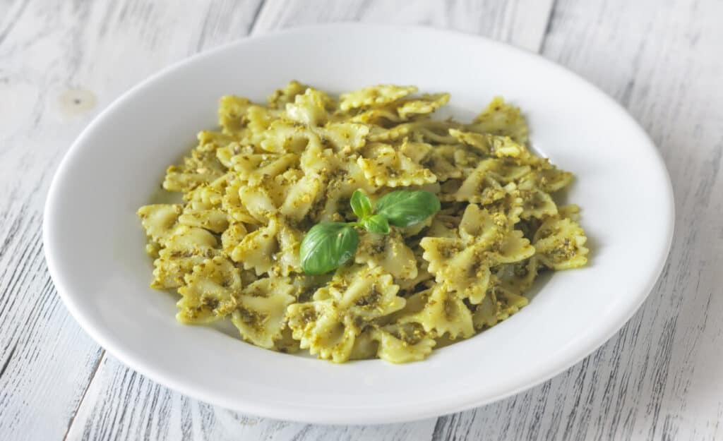 Farfalle with pesto on the white wooden table