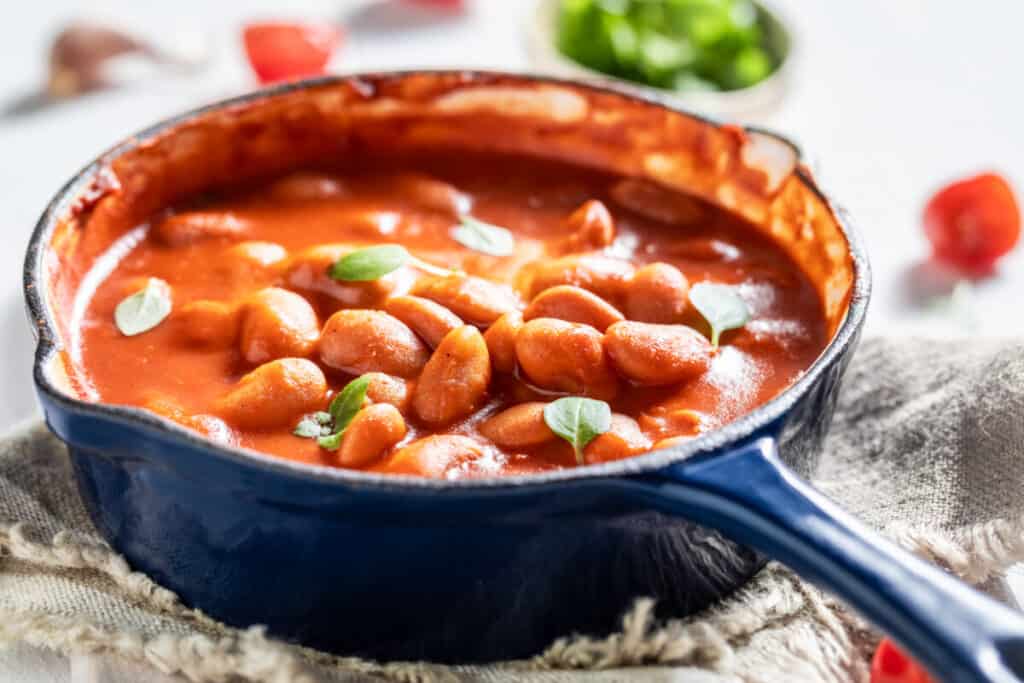 Hot baked beans with garlic and basil in a blue pan