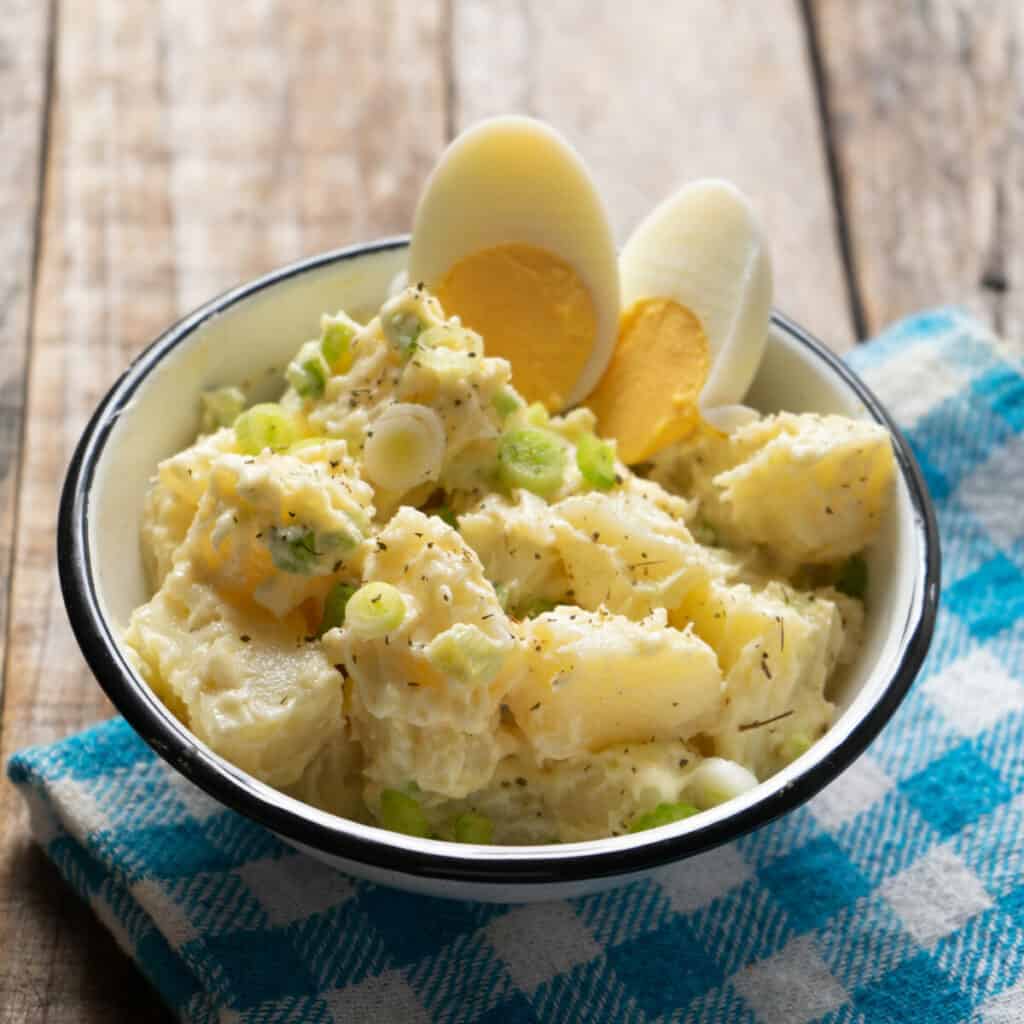Traditional potato salad with egg and mayonnaise on wooden background