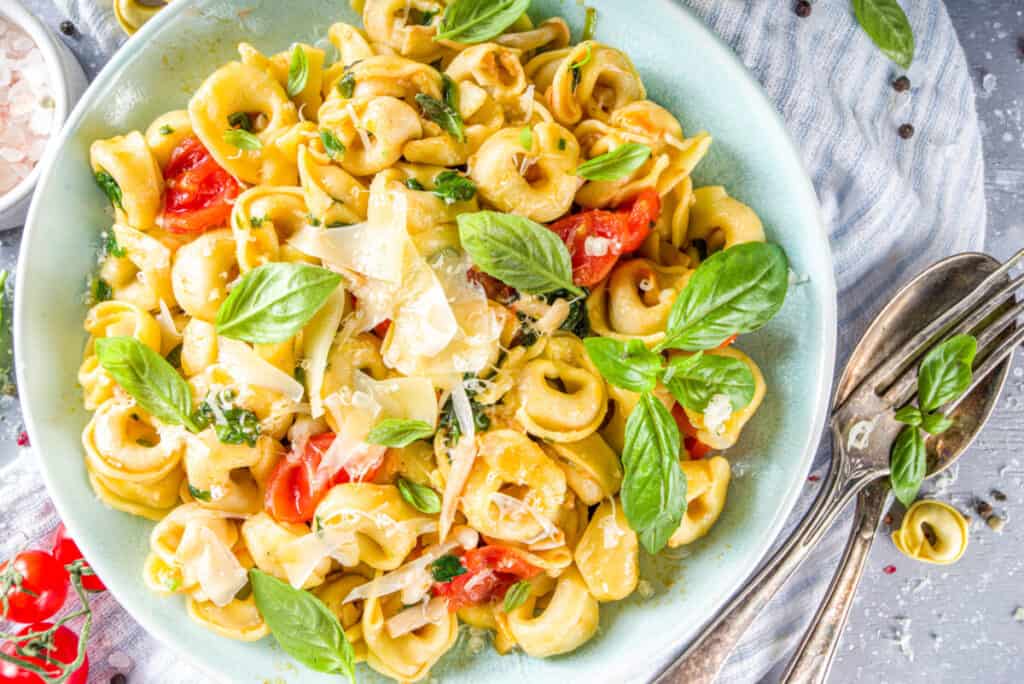 Tortellini pasta with parmesan cheese, vegetables, spinach, tomatoes, mushrooms and basil
