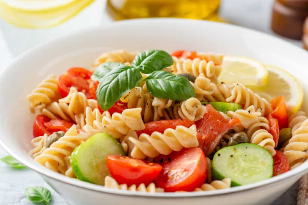 Whole wheat pasta salad with cucumbers, cherry tomatoes, salted salmon, and capers