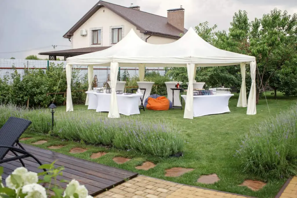 Elegant summer backyard barbecue with a white tent and white table cloths.