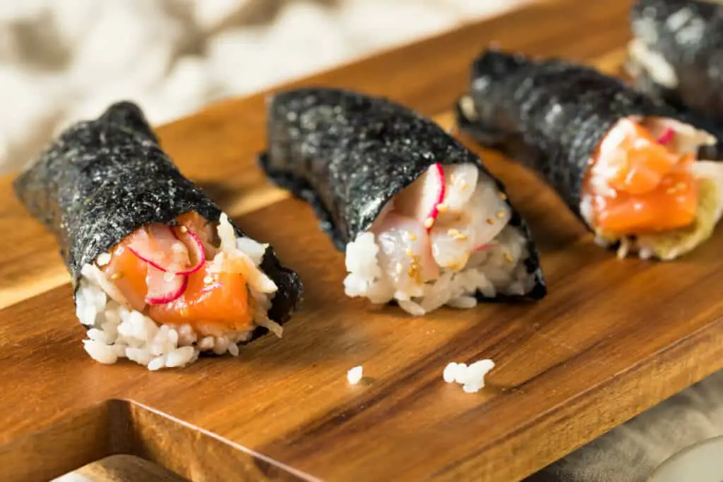 Homemade sushi temaki hand rolls with salmon and fish.