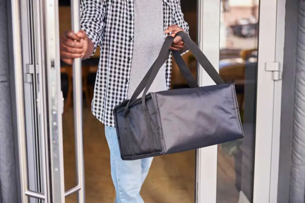 Man in checkered shirt holding insulated thermal  bag