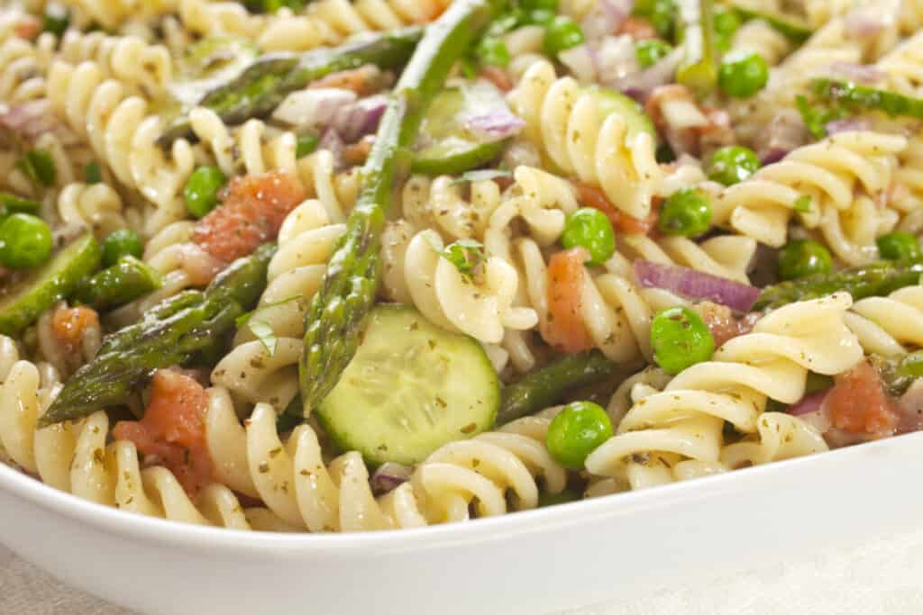 Pasta salad made with asparagus, peas, red onion, and cucumber.