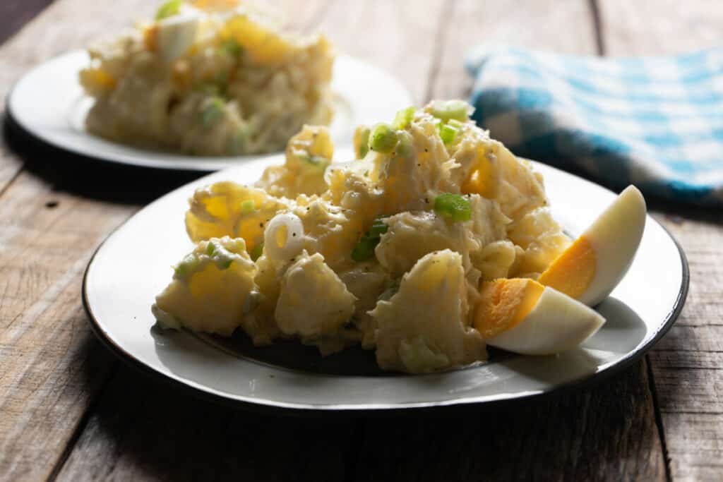 Traditional potato salad with egg and mayonnaise on wooden background.