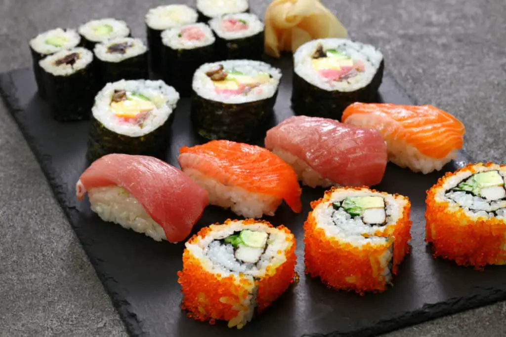 A variety of colorful sushi with salmon, tuna, fish eggs, avocado, and imitation crab.