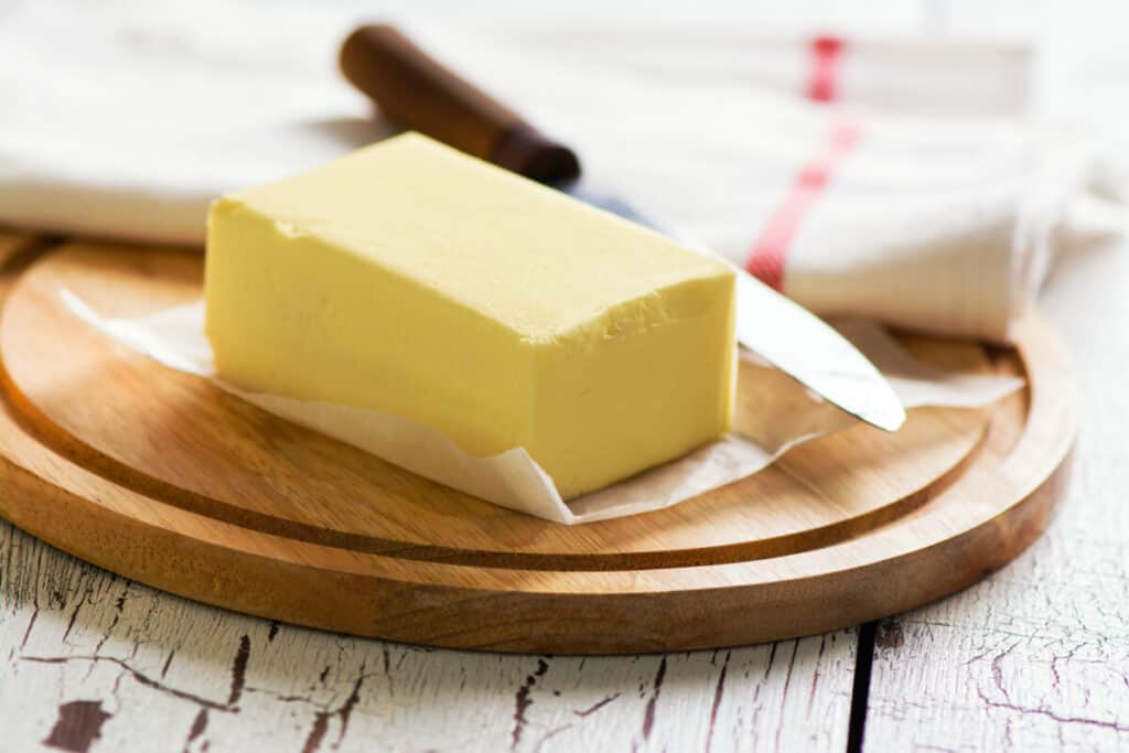 Butter block and knife on a wooden cutting board.