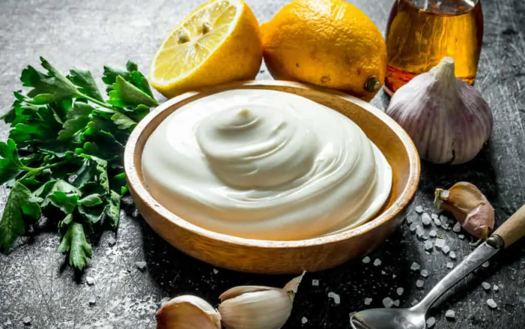 Mayonnaise with parsley, lemon and garlic on a dark rustic background.