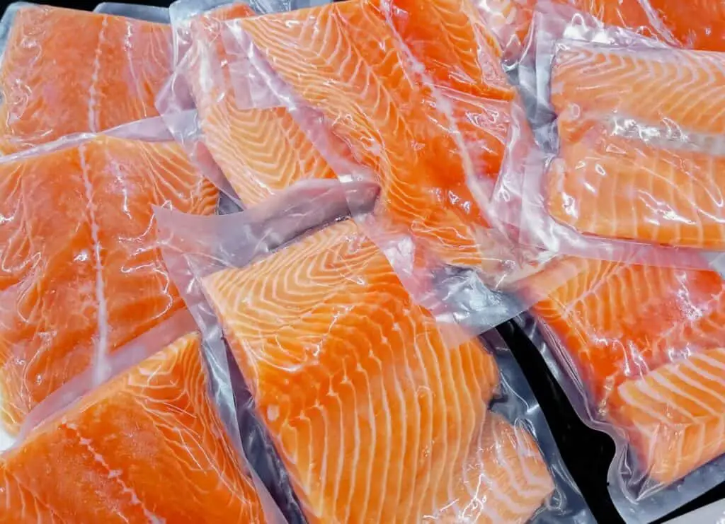 Raw, frozen salmon in plastic packaging.