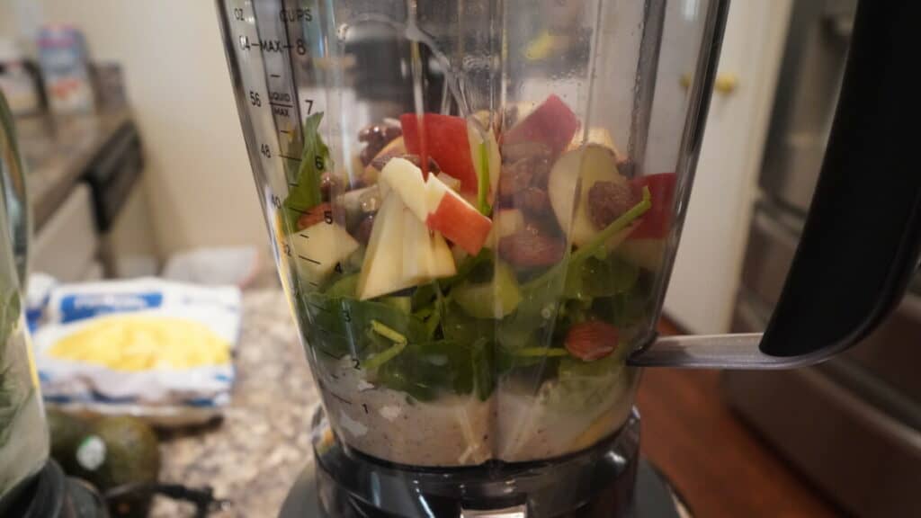 Blender with apples, celery, spinach, almonds, and nut milk.