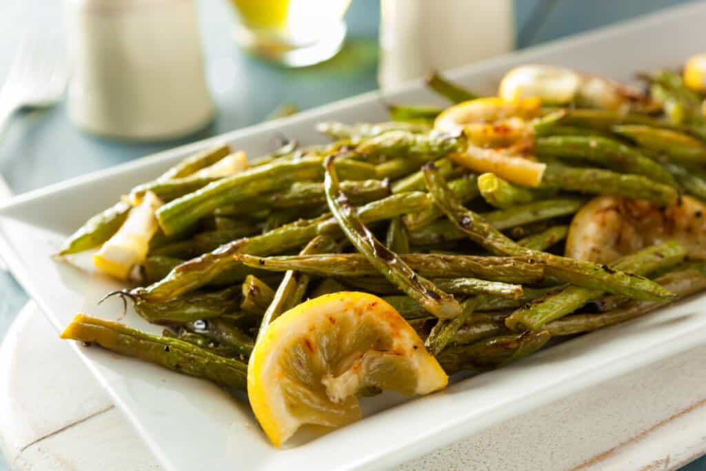 Sauteed green beans with lemon and garlic on a white plate.