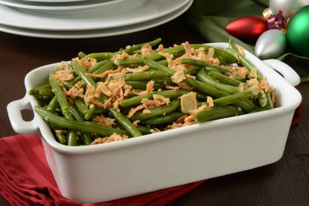 Green beans with crispy fried onions in a white casserole dish.