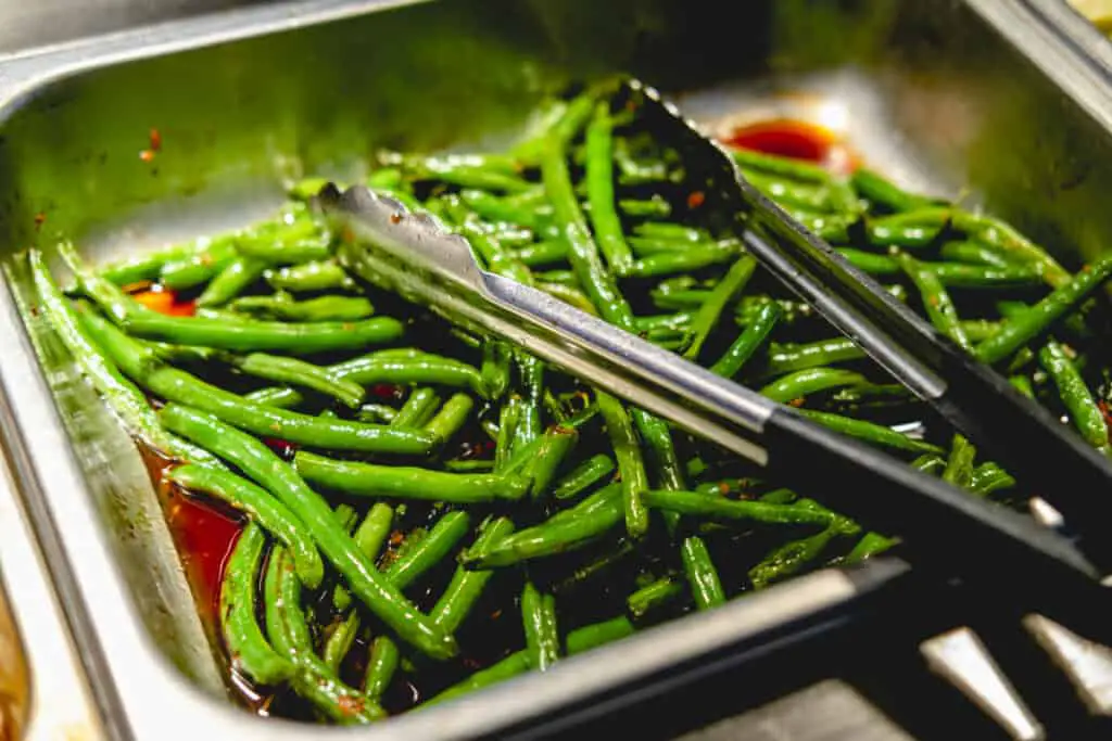 Green beans with teriyaki sauce in a chafing dish.