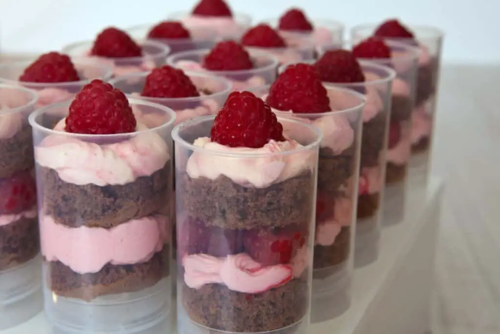 Layered chocolate cake cups with chocolate frosting and raspberries.