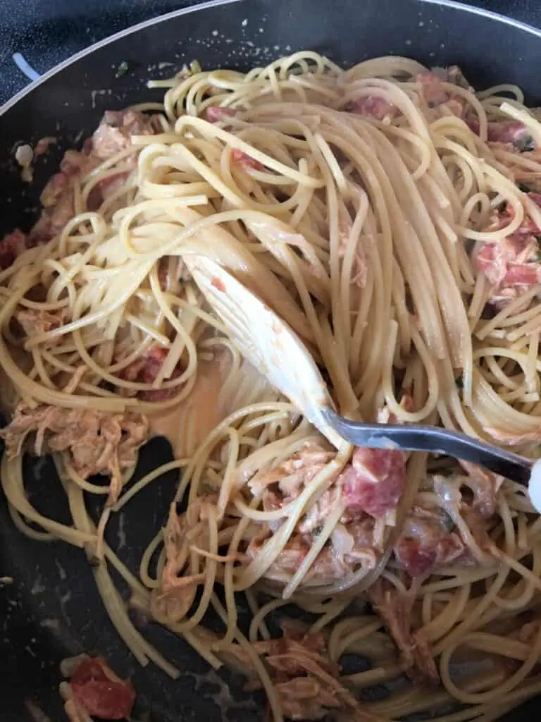 spaghetti being mixed into the other ingredients